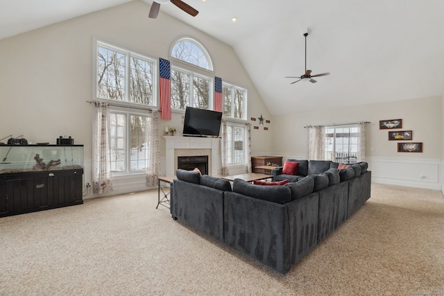 carpeted living room featuring ceiling fan, a fireplace, a wealth of natural light, and wainscoting