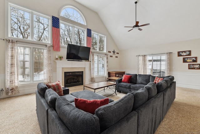 living area with carpet, wainscoting, a fireplace with flush hearth, and a healthy amount of sunlight