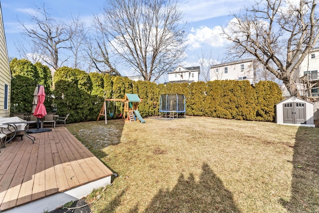 view of yard with a trampoline, a storage unit, a playground, and an outbuilding