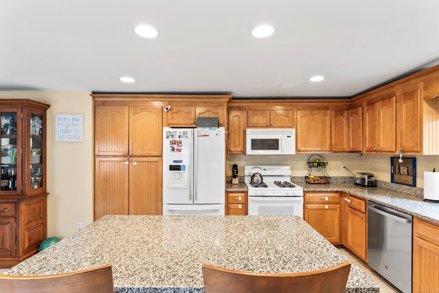 kitchen featuring white appliances, recessed lighting, light stone counters, and a center island