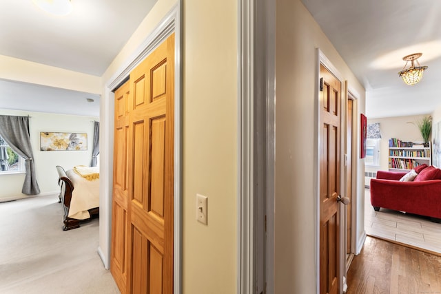 hall featuring light wood-type flooring and baseboards