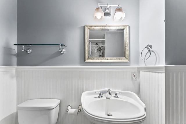 bathroom featuring a wainscoted wall, a sink, and toilet