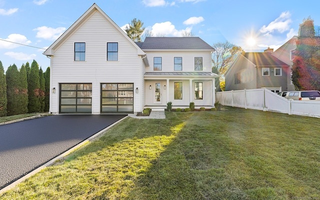 view of front of house featuring an attached garage, covered porch, fence, driveway, and a front yard