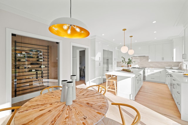 dining space with recessed lighting, light wood-style flooring, and crown molding