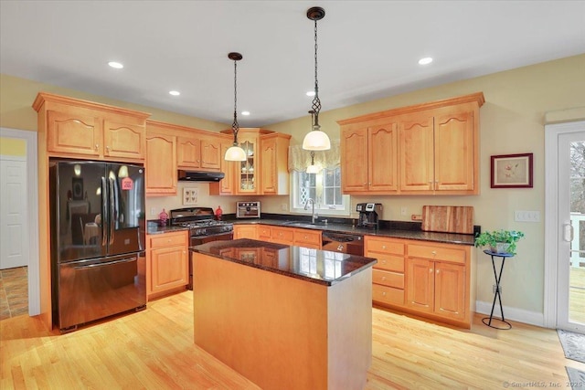 kitchen featuring light wood-type flooring, a sink, black appliances, and light brown cabinetry