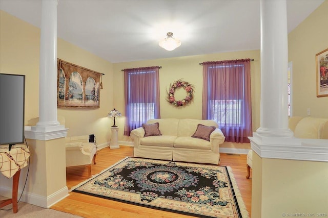 living area featuring decorative columns, light wood-style flooring, and baseboards