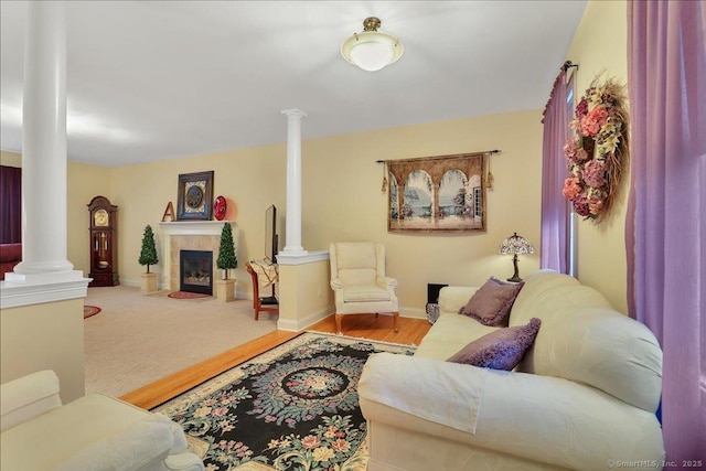 living area featuring carpet flooring, a tile fireplace, decorative columns, and baseboards