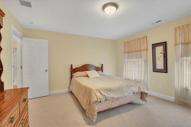 bedroom featuring baseboards, visible vents, and light colored carpet