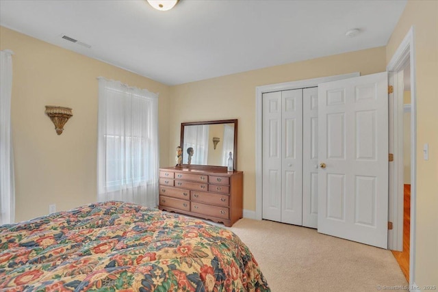 bedroom featuring a closet, visible vents, and light carpet