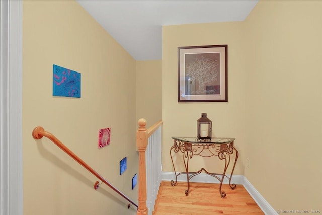 corridor featuring baseboards, an upstairs landing, and wood finished floors