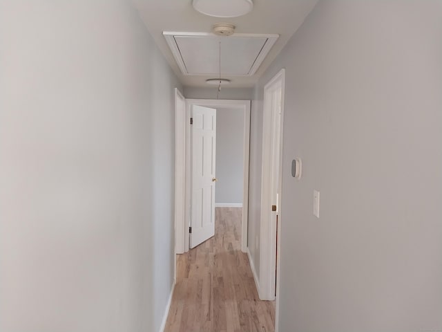 hallway with attic access, baseboards, and light wood finished floors