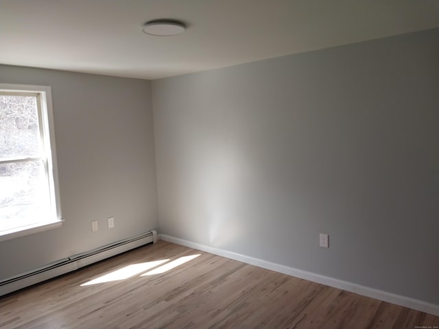 empty room with baseboards, baseboard heating, and wood finished floors