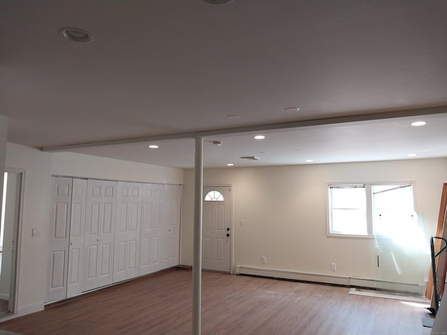 below grade area featuring a baseboard heating unit, recessed lighting, and wood finished floors