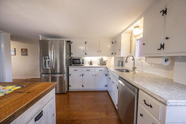 kitchen featuring stainless steel appliances, a sink, white cabinets, light countertops, and decorative backsplash