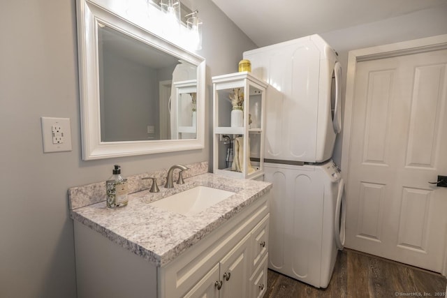 bathroom featuring stacked washing maching and dryer, wood finished floors, and vanity