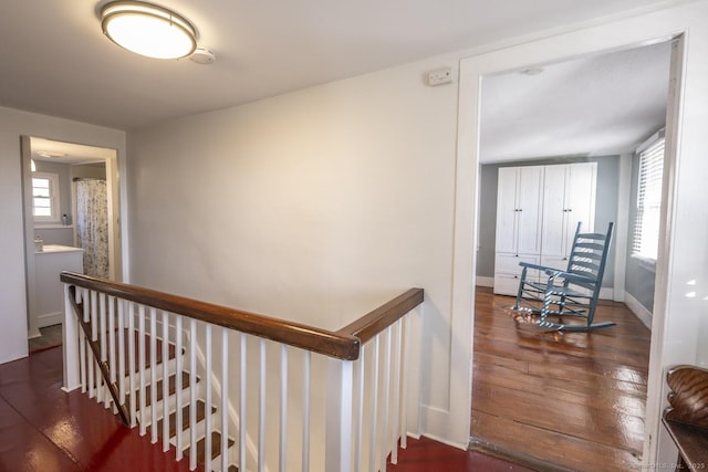 hall featuring baseboards, dark wood-type flooring, and an upstairs landing