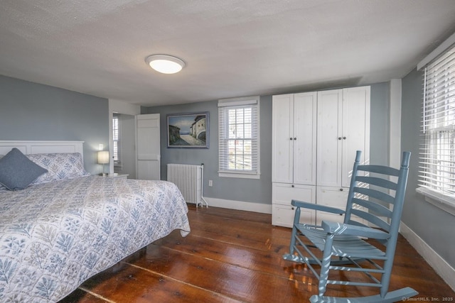 bedroom with radiator, a textured ceiling, baseboards, and dark wood-style flooring