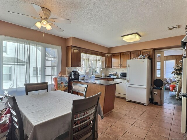 51 Milton Ave, Waterbury, CT 06706 - kitchen featuring visible vents, freestanding refrigerator, a peninsula, a sink, and light tile patterned flooring