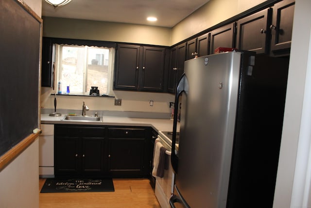 kitchen featuring stainless steel appliances, a sink, light countertops, and light wood-style floors