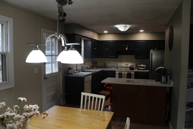 kitchen with electric range, freestanding refrigerator, a peninsula, range hood, and light countertops