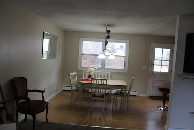 dining room with baseboard heating, a textured ceiling, baseboards, and wood finished floors