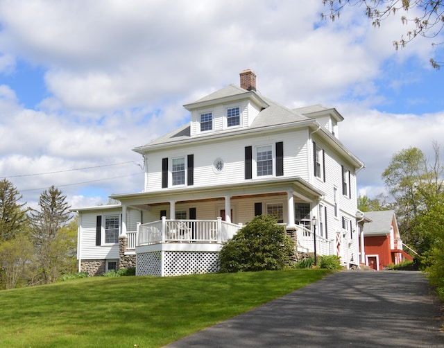 view of front facade with a porch, a front lawn, and a chimney