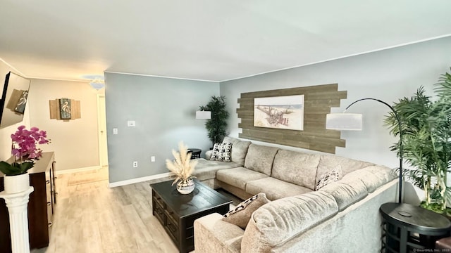 living area featuring light wood-type flooring, baseboards, and crown molding