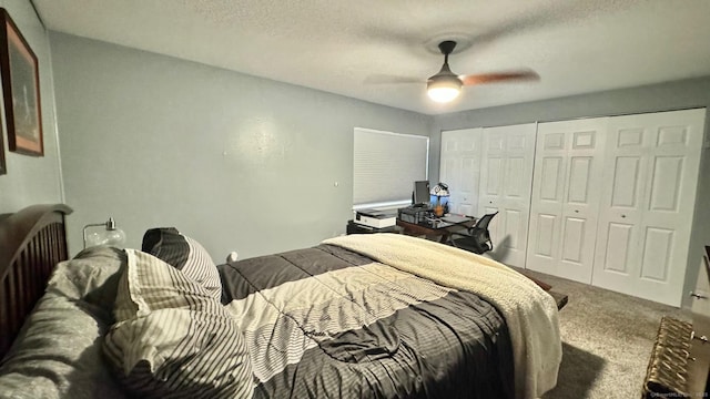 carpeted bedroom featuring a textured ceiling, two closets, and a ceiling fan