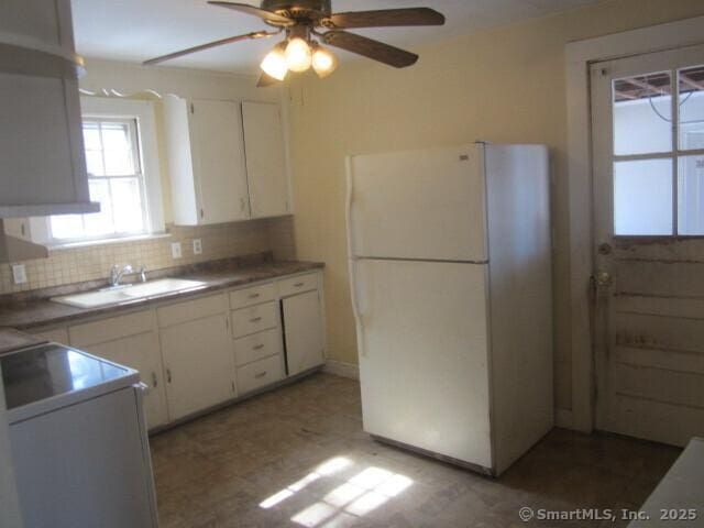 242 Elm St, Enfield, CT 06082 - kitchen with freestanding refrigerator, a sink, white cabinetry, a ceiling fan, and tasteful backsplash