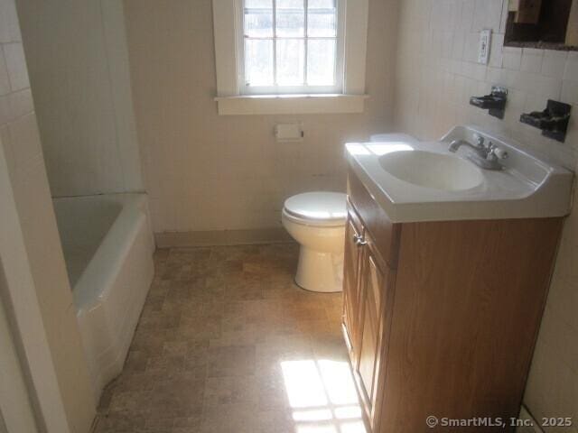 242 Elm St, Enfield, CT 06082 - bathroom with toilet, vanity, a tub to relax in, tile walls, and decorative backsplash