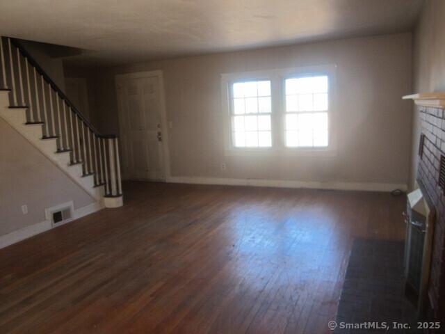 242 Elm St, Enfield, CT 06082 - unfurnished living room with a fireplace, baseboards, wood finished floors, and stairway