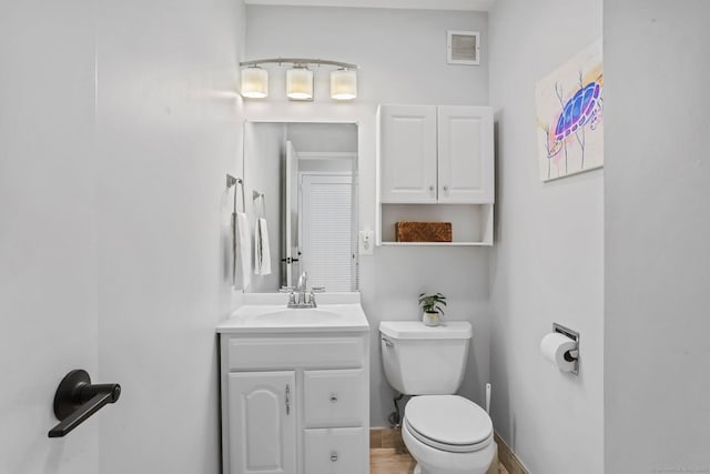 bathroom featuring baseboards, visible vents, vanity, and toilet