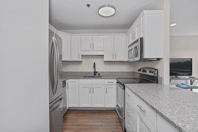 kitchen featuring white cabinets, light stone counters, appliances with stainless steel finishes, dark wood-type flooring, and a sink