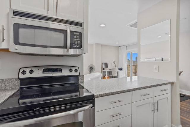 kitchen with stainless steel appliances, visible vents, white cabinets, light stone countertops, and dark wood-style floors