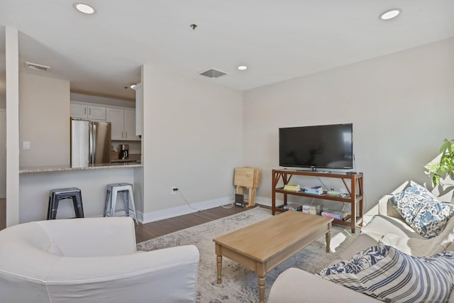 living area featuring baseboards, visible vents, wood finished floors, and recessed lighting