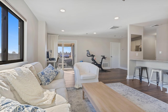 living room with baseboards, visible vents, wood finished floors, and recessed lighting