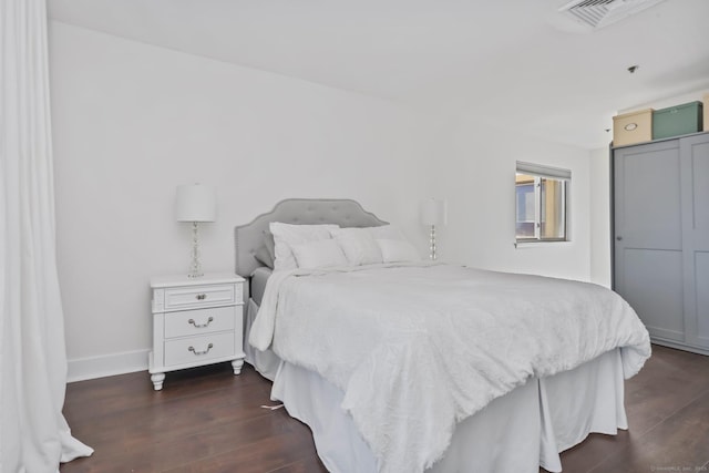 bedroom with dark wood-type flooring, a closet, visible vents, and baseboards