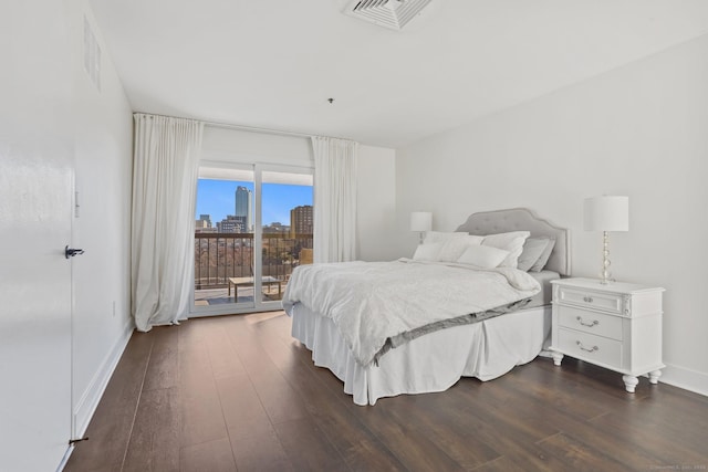 bedroom featuring dark wood-type flooring, access to outside, visible vents, and a view of city