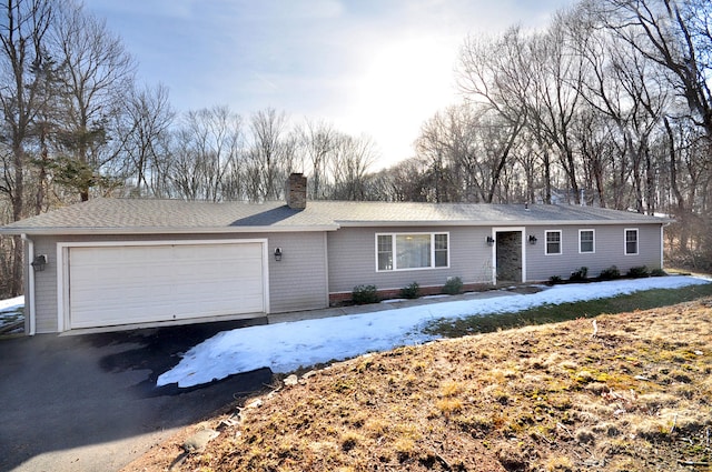 ranch-style home with driveway, a chimney, and an attached garage