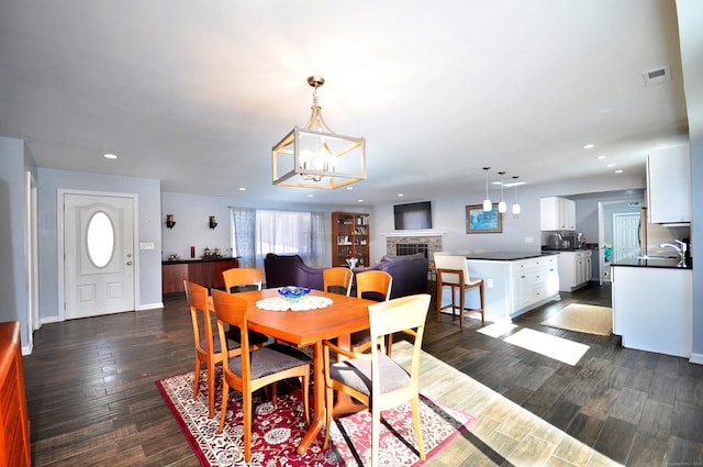 dining area featuring a fireplace, visible vents, dark wood finished floors, and recessed lighting