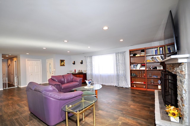 living area featuring recessed lighting, a stone fireplace, baseboards, and wood finished floors