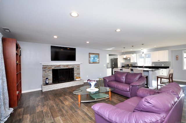 living area with recessed lighting, a fireplace, visible vents, baseboards, and dark wood-style floors