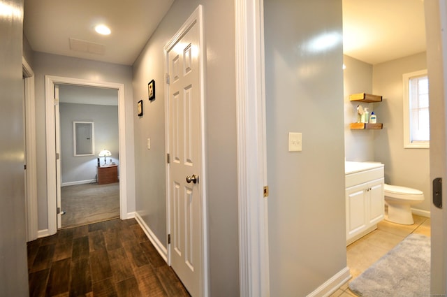 corridor with visible vents, baseboards, and wood finished floors