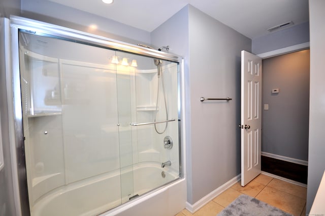 bathroom featuring shower / bath combination with glass door, tile patterned flooring, visible vents, and baseboards