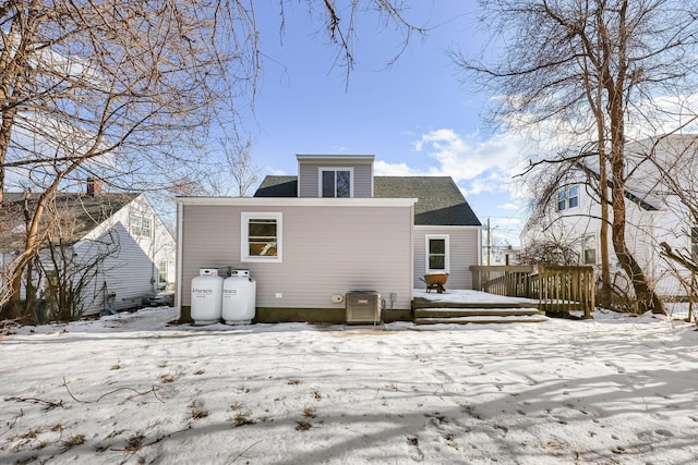 snow covered house featuring a shingled roof and a deck