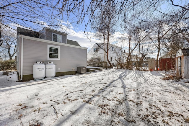 snow covered back of property with central air condition unit and fence