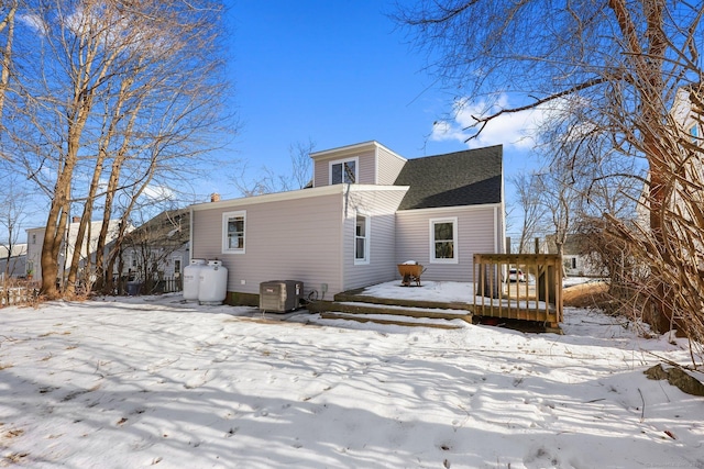 snow covered house featuring roof with shingles, a wooden deck, and central air condition unit