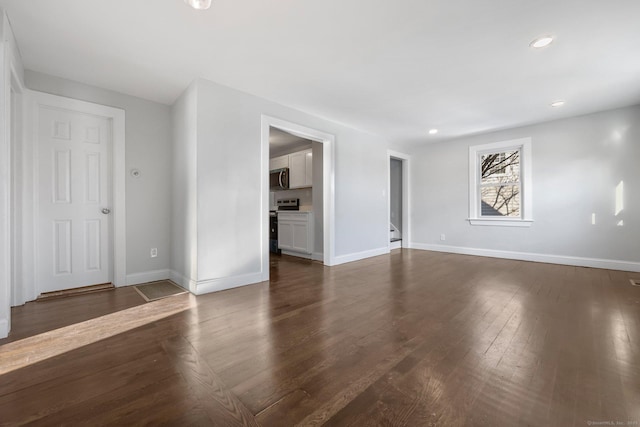 unfurnished living room featuring baseboards, dark wood-type flooring, and recessed lighting