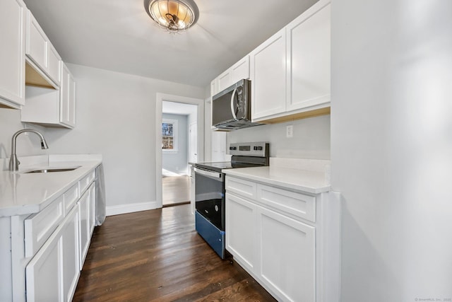 kitchen featuring stainless steel microwave, dark wood-type flooring, light countertops, a sink, and range with electric stovetop