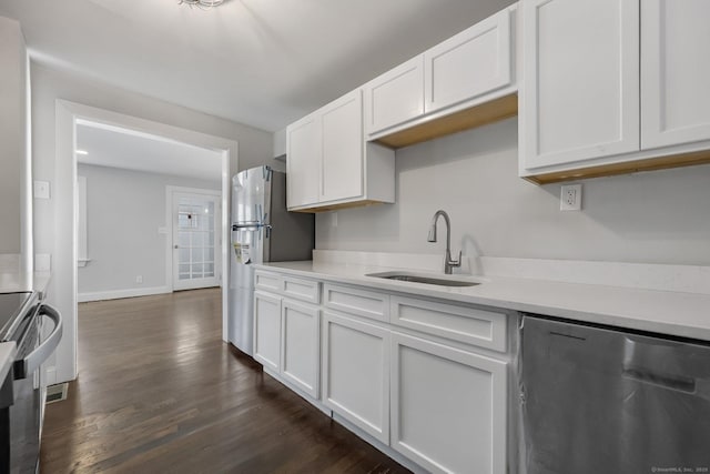 kitchen with dark wood finished floors, light countertops, appliances with stainless steel finishes, white cabinetry, and a sink